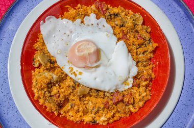 Bir tabak migas (kırıntılar), geleneksel olarak bayat ekmek ve diğer malzemelerden (kıymalı et ve sebze) yapılan İspanya ve Portekiz 'den bir mutfak hazırlığı, yanında da kızarmış yumurta.