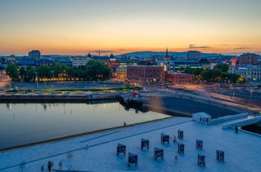 OSLO, NORway - 10 Temmuz 2014: Norveç 'in Oslo şehrinin günbatımı manzarası, 2003 ve 2007 yılları arasında Norveçli mimarlık firması Snohetta' nın mimarları tarafından tasarlanan Oslo Opera Binası 'nın modern binasından