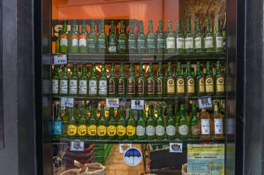 LUARCA, İspanya - SEPTEMBER 2, 2022: Asturias 'ın kuzeyindeki Luarca kasabasındaki bir Asturya ürünleri mağazasının vitrininde, tipik bir yerel ürün olan çeşitli şişe elma şarabı sergilenmektedir.