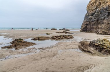 RIBADEO, İspanya - 30 AĞUSTOS 2022: Katedraller Plajı 'nı (Playa de las Catedrales) ziyaret eden insanlar, Galiçya' nın kuzeyindeki Ribadeo kentinde Doğal Anıt ilan ettiler. Adı uçurum oluşumlarından türetilmiştir. Karakter