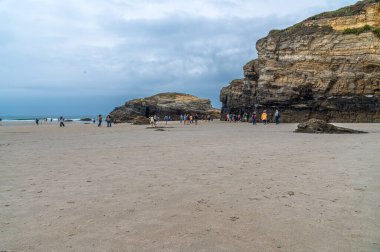 RIBADEO, İspanya - 30 AĞUSTOS 2022: Katedraller Plajı 'nı (Playa de las Catedrales) ziyaret eden insanlar, Galiçya' nın kuzeyindeki Ribadeo kentinde Doğal Anıt ilan ettiler. Adı uçurum oluşumlarından türetilmiştir. Karakter