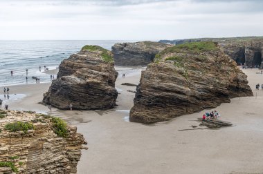 RIBADEO, İspanya - 30 AĞUSTOS 2022: Katedraller Plajı 'nı (Playa de las Catedrales) ziyaret eden insanlar, Galiçya' nın kuzeyindeki Ribadeo kentinde Doğal Anıt ilan ettiler. Adı uçurum oluşumlarından türetilmiştir. Karakter