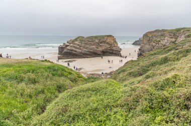 RIBADEO, İspanya - 30 AĞUSTOS 2022: Katedraller Plajı 'nı (Playa de las Catedrales) ziyaret eden insanlar, Galiçya' nın kuzeyindeki Ribadeo kentinde Doğal Anıt ilan ettiler. Adı uçurum oluşumlarından türetilmiştir. Karakter