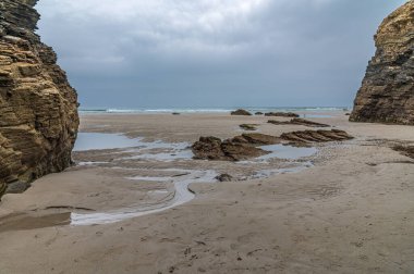 Cliff formations at the Beach of the Cathedrals (Playa de las Catedrales), declared a Natural Monument, in Ribadeo, Lugo province, Galicia, northern Spain. The characteristic features of the beach are natural arches and caves, which can be seen only  clipart