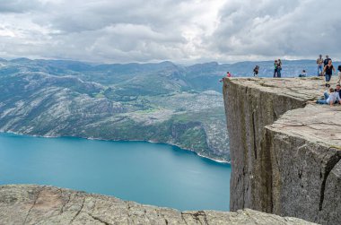 STRAND, NORway - 14 Temmuz 2014: Norveç 'in Rogaland kentinde Preikestolen (Kürsü Kayası) platformundaki insanlar, Lysefjorden' dan 604 metre yükseğe yükselen dik bir uçurum