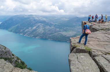 STRAND, NORway - 14 Temmuz 2014: Norveç 'in Rogaland kentinde Preikestolen (Kürsü Kayası) platformundaki insanlar, Lysefjorden' dan 604 metre yükseğe yükselen dik bir uçurum