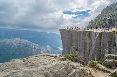 STRAND, NORway - 14 Temmuz 2014: Norveç 'in Rogaland kentinde Preikestolen (Kürsü Kayası) platformundaki insanlar, Lysefjorden' dan 604 metre yükseğe yükselen dik bir uçurum