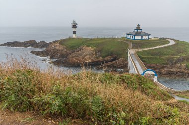 RIBADEO, SPAIN - SEPTEMBER 2, 2022: Ribadeo, Galiçya, İspanya 'nın iki deniz fenerine ev sahipliği yapan Pancha Adası manzarası: Şu anda turistik konaklama olarak yenilenmiş olan eski kare (19. yüzyılda inşa edilmiş) ve daha sonra yerine akıntı konmuştur.