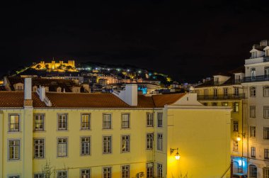 Lizbon, Portekiz 'deki eski Sao Jorge Kalesi' nin arka planında gece manzarası var.