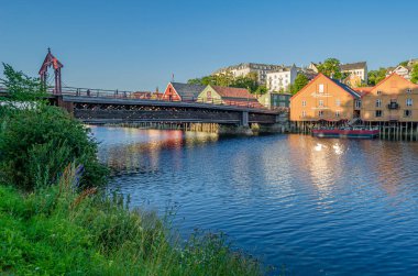 TRONDHEIM, NORWAY - JULY 23, 2014: View of old wooden storehouses flanking both sides of the Nidelva river in the old town of Trondheim, Norway clipart