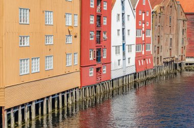 View of old wooden storehouses flanking both sides of the Nidelva river in the old town of Trondheim, Norway clipart