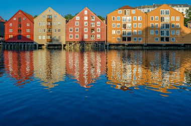 View of old wooden storehouses flanking both sides of the Nidelva river in the old town of Trondheim, Norway clipart