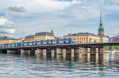 STOCKHOLM, SWEDEN - 27 Temmuz 2014: Stockholm metrosunun bir parçası olan metro treni (metrotrain), İsveç 'in eski Stockholm kentindeki bir köprüden geçmektedir.
