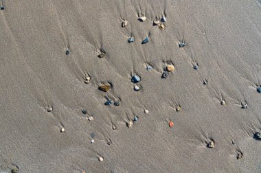 Kumsalda kıyıya vuran küçük taşlar.