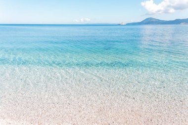 İtalya 'nın Elba Adası' nda kumsalı, berrak suyu ve güzel gökyüzü olan açık mavi deniz.