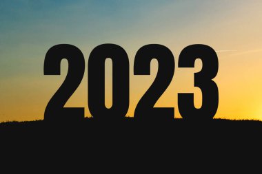 Yeni yıl 2023, gün batımında sahada. Takvim için poster. 2023 sayısının gölgesi