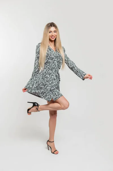 얼룩말 드레스에 다리에 발뒤꿈치를 패션의 아름다운 소녀가 배경으로 스튜디오에서 즐겁게 — 스톡 사진