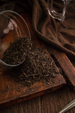 Lezzetli tuzlu çay yapraklarının makro fotoğrafçılığı kahverengi arka planda, ahşap eski bir tahta üzerine cam kavanozdan dökülmüş.