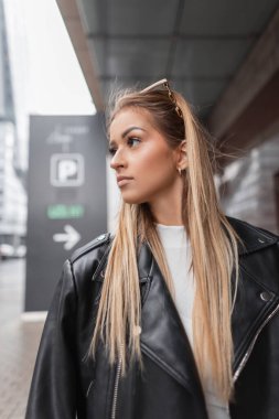 Moda derisinden siyah ceketli, şehirde beyaz elbiseli güzel bir kadın manken.