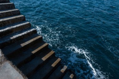 Vintage concrete stairs near the ocean with shadows and light. Minimalism photo and blue water