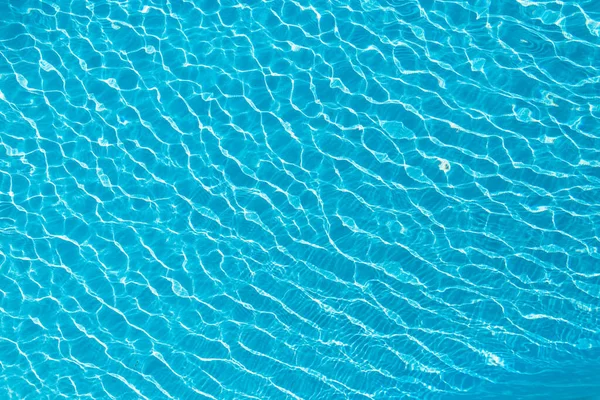 Blue beautiful water texture with waves and reflection in the pool, top view.