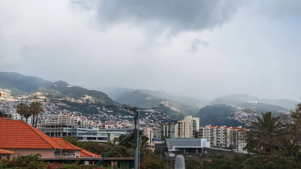 霧とマデイラ島の雲と山の背景に家と美しい都市 — ストック写真