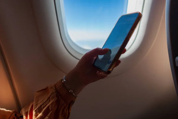 Business woman is flying in an airplane and using a smartphone. Travel and phone, concept