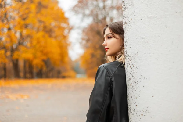 穿着黑色皮夹克的年轻漂亮姑娘在秋天的黄色公园里 — 图库照片