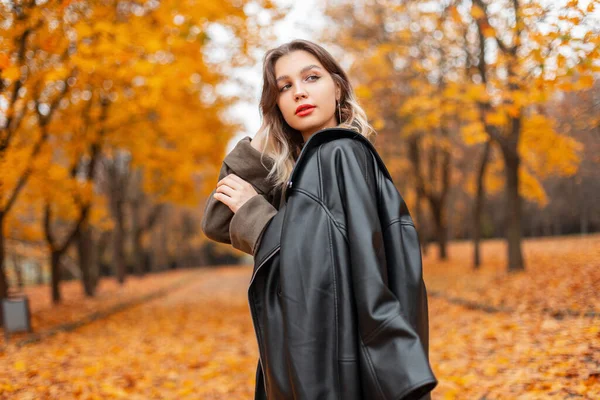 秋の公園を歩く流行の服で赤い唇を持つファッショナブルな美しい若い女性 — ストック写真