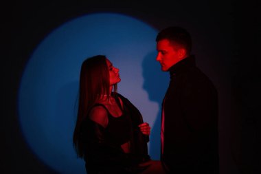 Tarz sahibi yakışıklı bir adam ve modaya uygun güzel bir kız koyu renk arka planda yaratıcı kırmızı mavi ışık