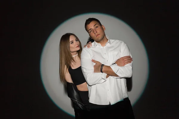 美しい若いカップルの美しい女性とハンサムな男でファッションカジュアル服で暗い背景にスタジオで創造的な円形の光 — ストック写真