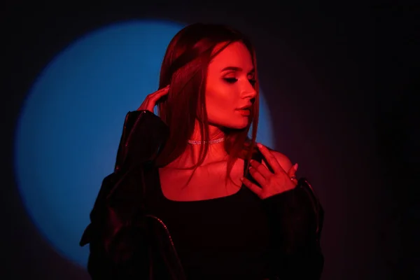 Beauty woman in black fashion clothes with creative red light on a dark background with blue circle light