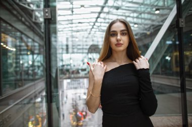 Modern bir ofis binasında cam duvarın yanında şık siyah elbiseli güzel moda genç kadın modeller.