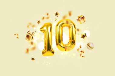Gold festive balloons 10 with golden confetti, presents, mirror ball and stars fly on a beige background with bokeh lights and sparks. Birthday luxury party ten card, a creative idea