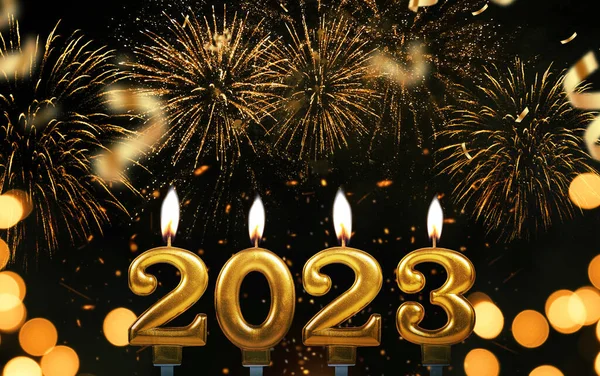 New Year\'s Eve 2023. Gold candles 2023 burning on a black background with fireworks and confetti. Happy New Year
