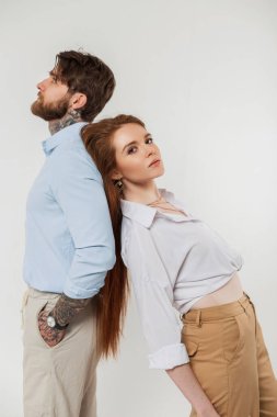 Modayı takip eden güzel, zarif âşıklar, şık giyinen yakışıklı erkekler ve güzel kadınlar beyaz arka planda sırt sırta dururlar.