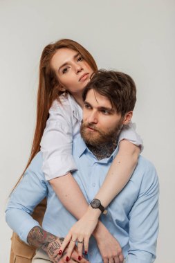 Moda modası geçmiş hippi çift güzel kadın ve şık gömlekli yakışıklı vahşi adam stüdyoda beyaz bir arka planda oturur ve sarılırlar.