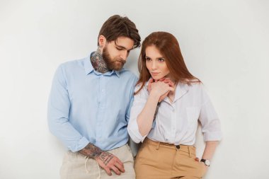 Moda çifti, güzel bir kadın ve beyaz bir arka planda şık giyinmiş sakallı ve saç stili olan yakışıklı bir adam.