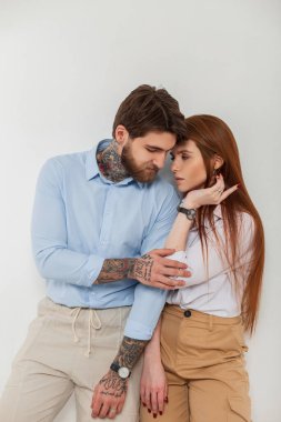 Güzel bir çift, şık kızıl saçlı manken ve şık şık giyinen yakışıklı hippi beyaz arka planda stüdyo gömleği.