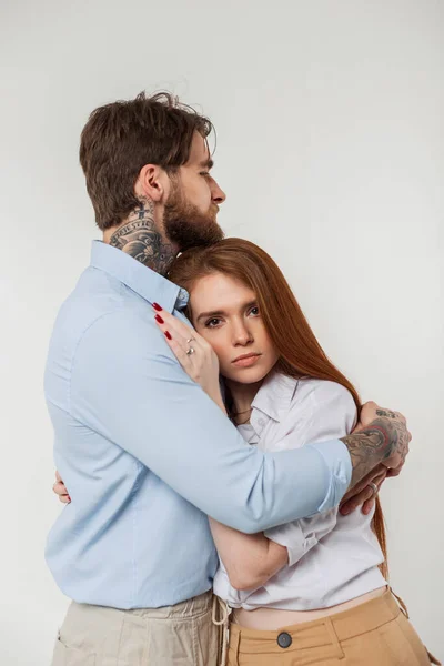 Beautiful fashion couple beauty redhead woman and handsome man in casual stylish elegant outfit hug on a white background in studio