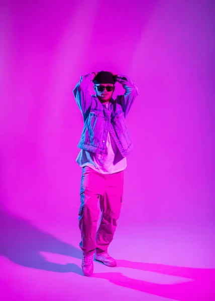 stock image Fashionable male dancer in stylish clothes dancing in a creative studio with pink and neon lights