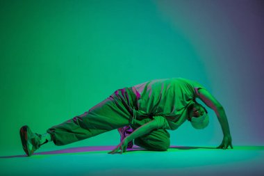 Profesyonel dansçı şık elbiseli bir adam. Cyan ve mor ışıklarla yaratıcı bir stüdyoda dans ediyor.