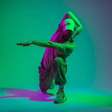Stüdyoda yeşil ve mor ışıkla dans eden şık giyimli şık hip hop dansçısı.