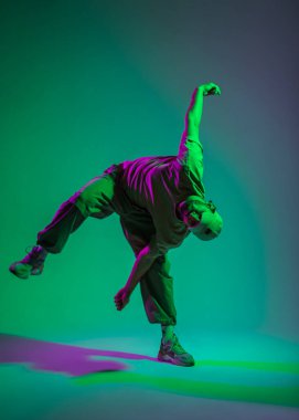 Modadan anlayan profesyonel hip hop dansçısı modaya uygun giyinmiş, şapkalı, eflatun renkli yaratıcı stüdyosunda dans eden biri.