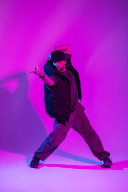 Moda kıyafetli şık profesyonel dansçı. Pembe ve neon ışıklı yaratıcı renkli bir stüdyoda dans ediyor.
