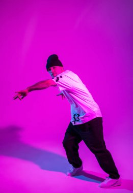 Profesyonel break dansçı yaratıcı renkli stüdyoda pembe ve neon ışıkla dans ediyor.