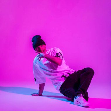 Moda kıyafetleri içinde havalı profesyonel dansçı çocuk pembe ve neon ışıklı yaratıcı bir stüdyoda dans ediyor.