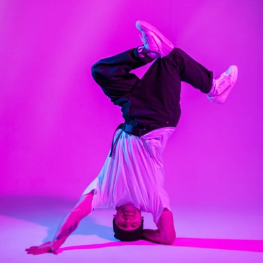 Modaya uygun, hippi dansçı çocuk. Tek koluyla dans ediyor. Pembe ve neon ışıklı yaratıcı bir stüdyoda.