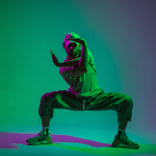 Fashion man dancing in creative color studio with cyan and pink light