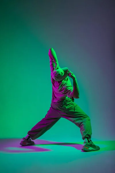 stock image Stylish professional dancer man with a cap in trendy fashion clothes dancing in a colorful creative studio with cyan and pink lights